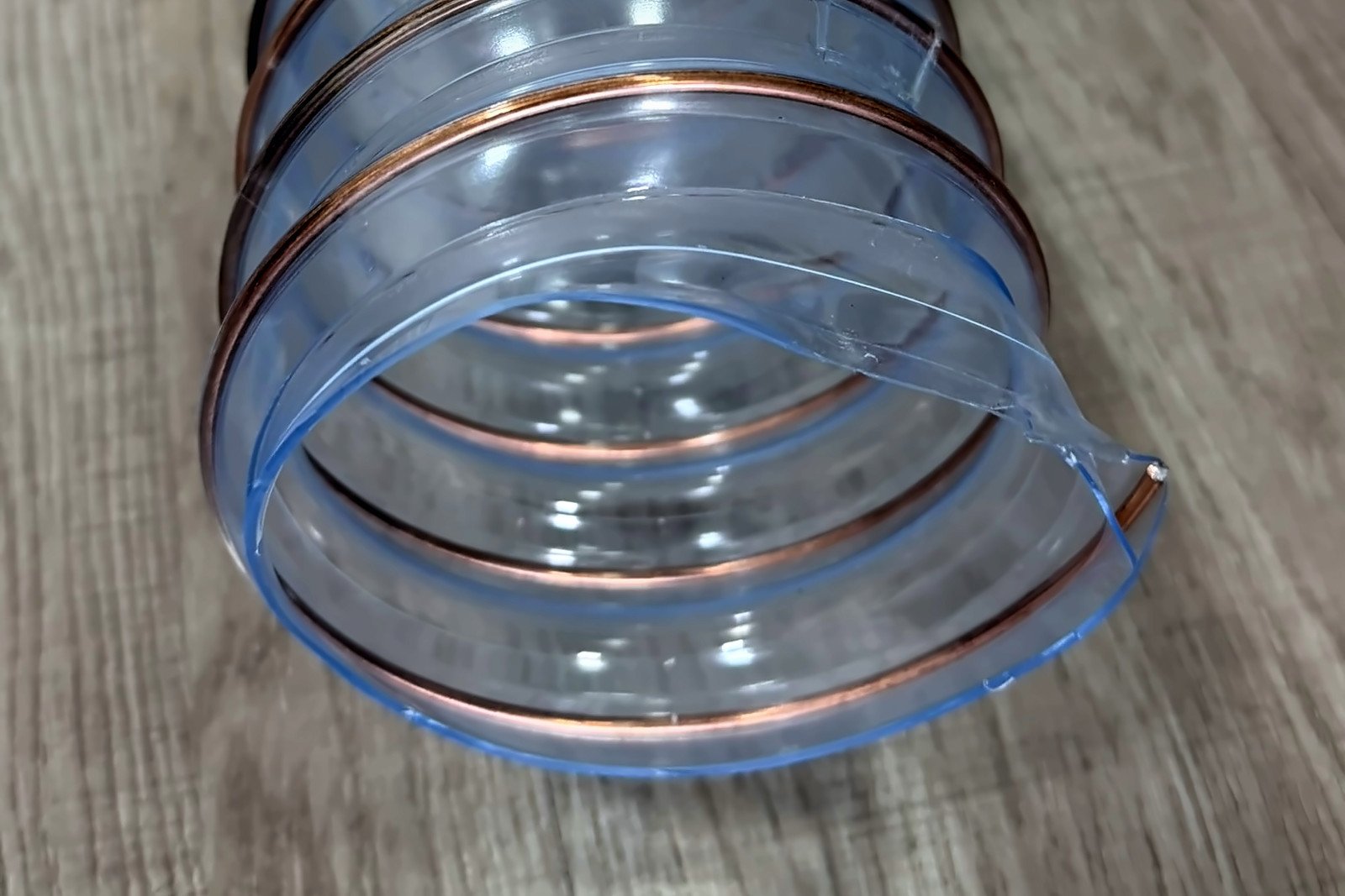 Ponta de mangueira de poliuretano transparente com espiral de aço cobreado embutida na parede, vista de perto